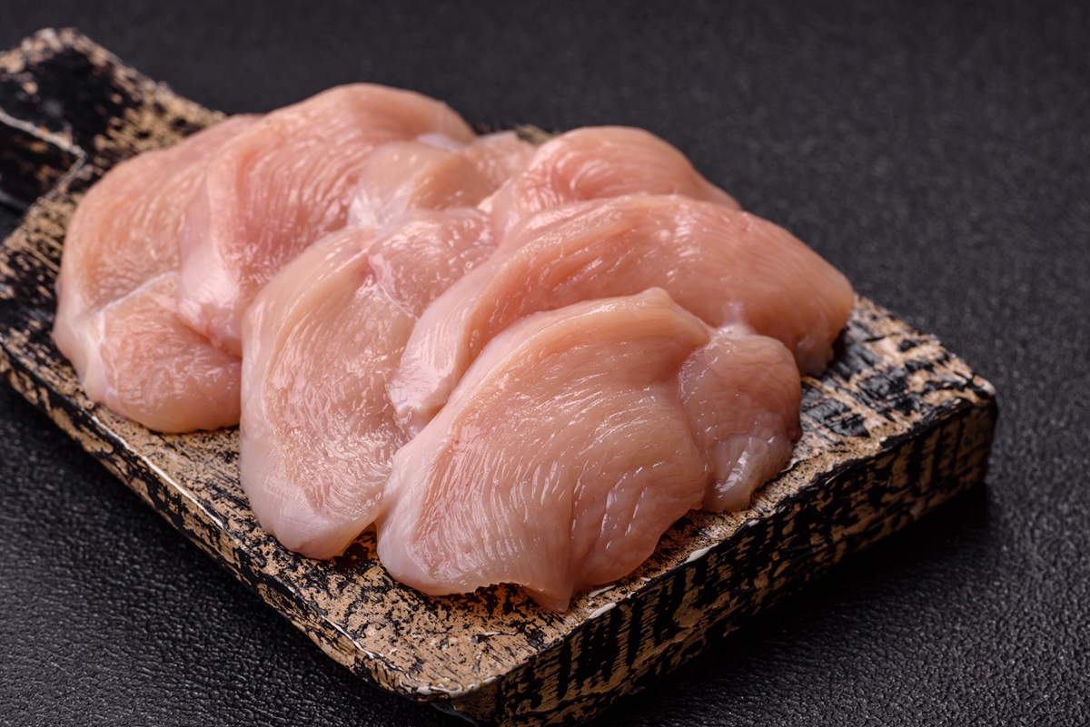 Stykker af rå kylling ligger på et skærebræt